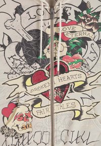 Kurtka z kapturem na zamek, zdobiona graficznymi nadrukami, różami, czaszkami i tekstem. Paleta kolorów obejmuje kremowy, czerwony, czarny i zielony z teksturowanymi detalami.