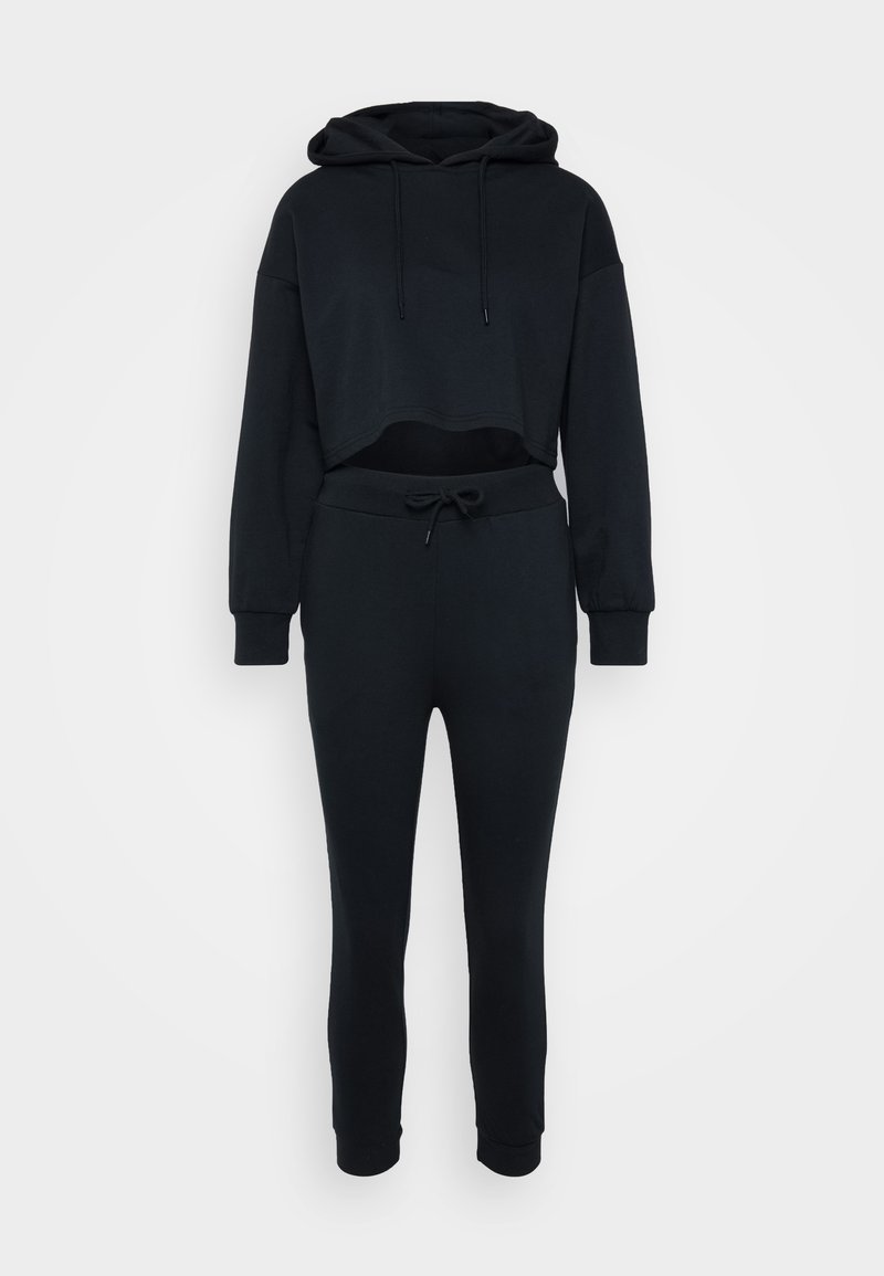 Schwarze, cropped Kapuzenjacke mit Kordelzug und passenden, schmal zulaufenden Jogginghosen. Weicher Stoff, gerippte Bündchen und Bund mit verstellbarem Kordelzug.