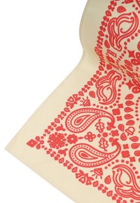 Beżowy materiał z czerwonymi wzorami paisley i kwiatowymi wzdłuż krawędzi, z widocznym szczegółowym haftem na złożonym rogu.