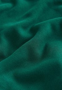 Mäkká, textúrovaná tkanina v hlbokej zelenej farbe so subtílnymi vlnitými vzormi, ktorá sa vyznačuje hladkým povrchom a rovnomerným, konzistentným povrchom.