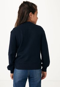 Marinblå stickad tröja med långa ärmar och ribbade muddar, med rund hals och en figurnära nederkant, visad från baksidan.