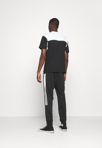 Black and white short-sleeve t-shirt with a color-blocked design, paired with black joggers featuring white side stripes and cuffs.