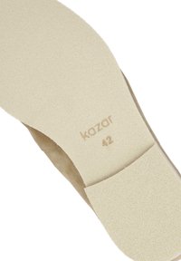 Végtelen színű, beige velúrbelső, texturált, törtfehér gumi talppal, amelyen a "kazar" felirat és a "42" méret szerepel az azonosítás érdekében.