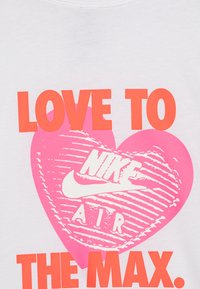 Balta marškinėliai su ryškiu rožiniu širdies grafiku ir užrašu "NIKE AIR", bei ryškiai oranžiniu tekstu "MEILĖ MAXIMUM".