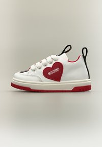 Baskets blanches avec semelle rouge, patch en forme de cœur rouge marqué Moschino sur le côté, languettes noires au talon et à la languette, et lacets blancs.