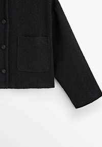 Mustapintainen teksturoitu neuletakki, jossa on nappikiinnitys edessä, pitkät hihat ja yksi etutasku, jossa on huomaamaton tikkausreuna.