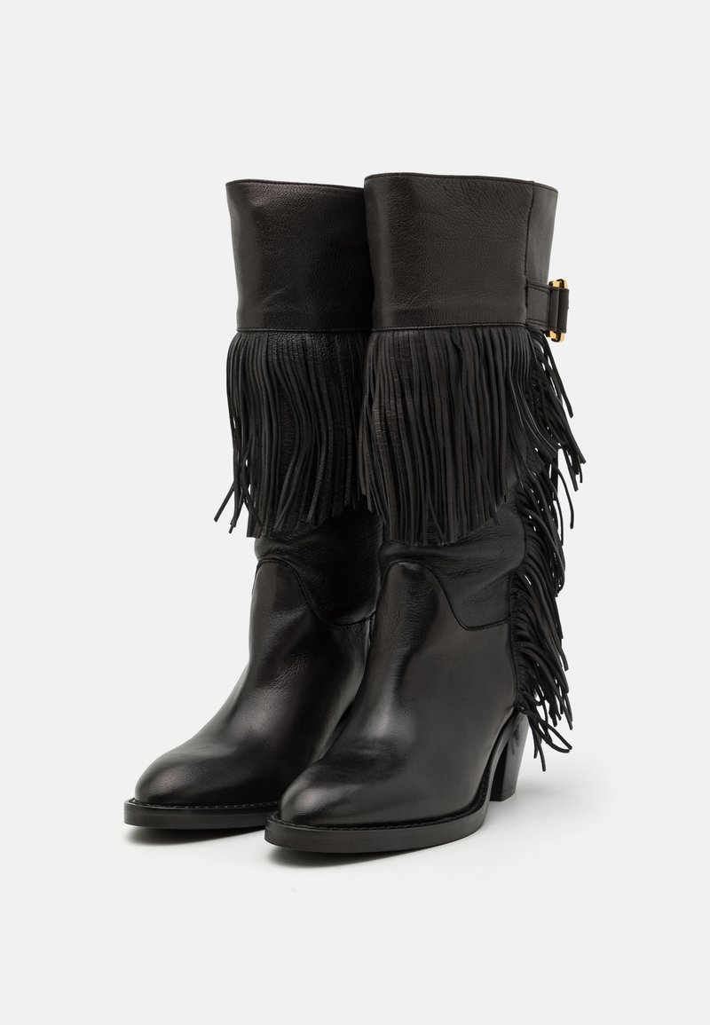 Black leather ankle boots with fringed detailing, a rounded toe, and stacked heel. Features a smooth texture and a buckle accent at the cuff.