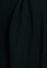 Donkergroene ribstof, met verticale lijnen en een zachte textuur, waarbij plooien subtiele diepte in de stof creëren.