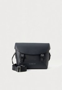 Zwarte leren boodschappentas met klepsluiting, voorzien van zilverkleurige metalen accenten en verstelbare schouderriem. Logo zichtbaar op de voorkant.