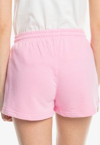 Růžové bavlněné šortky s elastickým pasem, s hladkým povrchem a lemovanými okraji. Design je jednoduchý a ležérní.