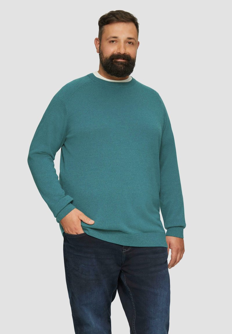 Türkiser Pullover mit Rundhalsausschnitt, langen Ärmeln, gerippten Bündchen und Saum, kombiniert mit dunkelbauen Jeans. Weiches Material, lässige Passform.