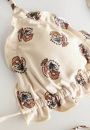 Biustonosz typu underwire w kwiatowy wzór, wykonany z miękkiego beżowego materiału, z falbanami na brzegach i marszczonymi detalami, w niebieskie i pomarańczowe kwiatowe wzory.