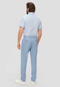 Camisa corta de manga azul claro con cuello, combinada con pantalones azul claro. El conjunto presenta un sutil patrón texturizado y bolsillos traseros.