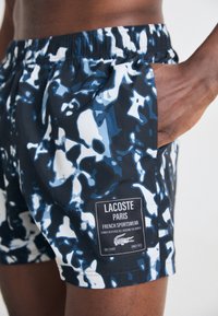 Schwimmshorts in einem blau-schwarzen Camouflage-Muster, mit einem gewebten Stoff, elastischem Bund und einem Markenetikett.