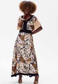 Maxi-jurk met een bloemenprint in beige, bruin en zwart. Kenmerkt zich door brede mouwen, een v-hals en een zwarte accent rond de taille. Soepele stoftextuur.