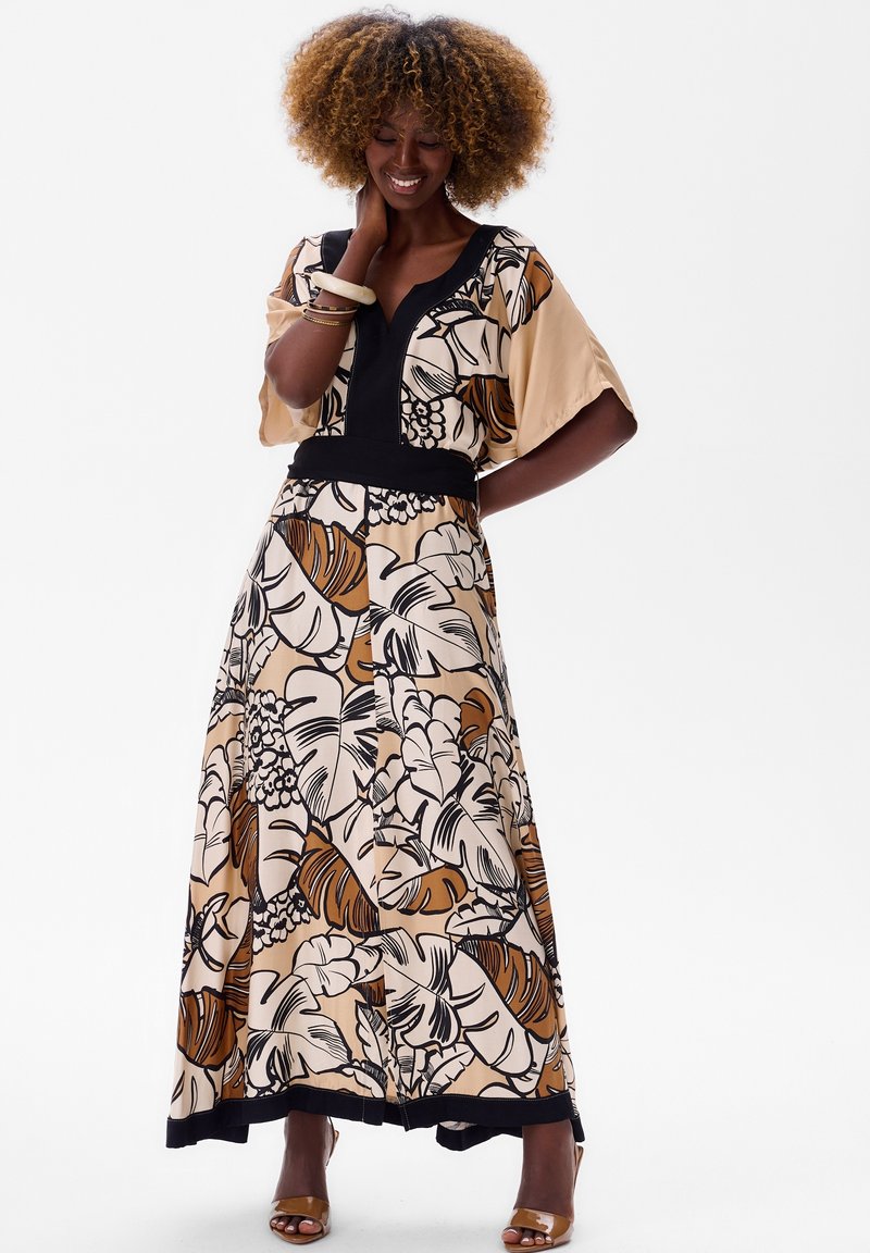 Maxi-jurk met een bloemenprint in beige, bruin en zwart. Kenmerkt zich door brede mouwen, een v-hals en een zwarte accent rond de taille. Soepele stoftextuur.