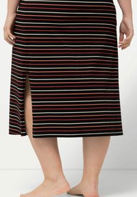 Gonna a metà lunghezza a righe nera, con strisce orizzontali in rosso e crema, dotata di uno spacco laterale e realizzata in tessuto morbido e elasticizzato.