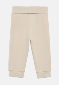 Pantaloni de trening bej, dintr-un material moale, cu talie elastică și manșete conice. Design simplu, fără modele sau accente.