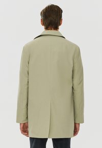 Jasnozielony płaszcz z zarysowanym kołnierzem, gładką fakturą, prostym krojem i jednym rozcięciem z tyłu. Dopasowany krój z długimi rękawami.