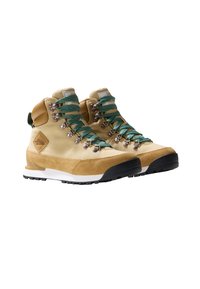 Hochformatige Wanderschuhe aus hellbeigem Wildleder und strapazierfähigem Stoff. Mit türkisfarbenen Schnürsenkeln, Metallöse und einer weißen Zwischensohle mit einer schwarzen Gummisohle.