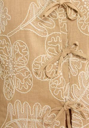 Pruun kangas valge lillemustriga tikandiga ja kolm seotud lipsu esiosas oleva ava ääres.