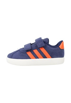 Zapatilla infantil azul marino con rayas naranjas y lengüeta en el talón, con dos tiras de velcro y suela de goma blanca, vista lateral.