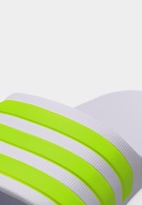 Λευκό σανδάλι με φαρδιές λωρίδες σε έντονο κίτρινο-πράσινο χρώμα οριζόντια τοποθετημένες στο πάνω μέρος, κοντινή όψη.