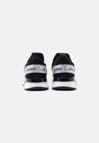 Μαύρα αθλητικά παπούτσια με διχτυωτό επάνω μέρος και μεταλλικές ασημένιες λεπτομέρειες. Διαθέτουν λογότυπο "Couture Version" στη φτέρνα και αντιθετική λευκή σόλα.