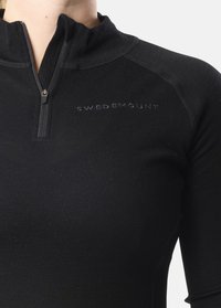 Black long-sleeve quarter-zip top made of a smooth, stretchy fabric. Features a high collar and subtle logo detail on the chest.