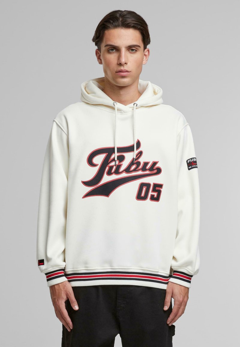 Hvit hettegenser med rød og svart "Fubu 05" grafikk, ribbet nederkant med svarte, røde og hvite striper, samt logo på ermet. Myk tekstur.