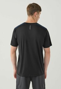 Sort atletisk t-shirt med korte ærmer, der har en rund halsudskæring og blå accenter på skuldrene. Bagsiden indeholder et reflekterende detalje.