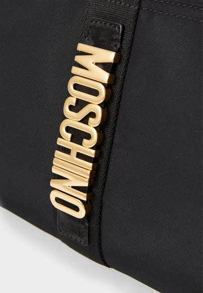 Melnas auduma soma ar lielu zelta "MOSCHINO" logotipu malā, gluda tekstūra ar kontrastējošu ādas akcentu.