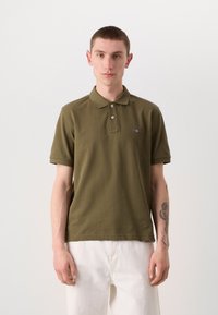 Oliven grøn polo skjorte med klassisk krave, to knapper, korte ærmer og et subtilt logo på brystet; lavet af tekstureret bomuldsstof.