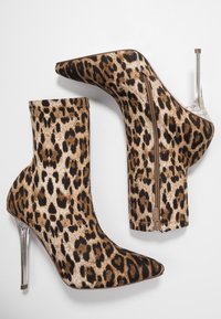 Bottes de cheville imprimé léopard avec un bout pointu et un talon aiguille transparent ; dotées d'une fermeture éclair sur le côté et d'un tissu texturé.