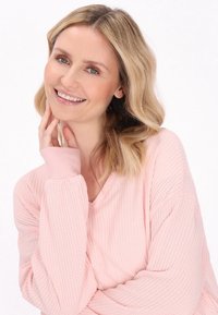 Top a maniche lunghe a maglia waffle di colore rosa chiaro con scollatura a V e polsini a costine. Tessuto morbido con vestibilità comoda, caratterizzato da un dettaglio di design sottile.