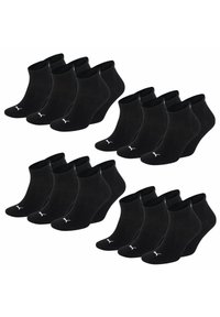 Schwarze Baumwollknöchelsocken, die in Sets angeordnet sind, mit einem gerippten Bund und einem dezenten weißen Logo am Knöchel. Sechs Paare werden in zwei Reihen gezeigt.