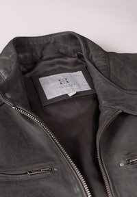Leather jacket in dark gray, featuring a zip closure, two exterior zip pockets, and a quilted interior lining with a brand label.