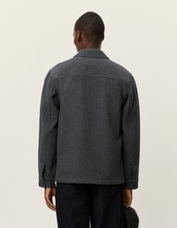 Donkergrijze visgraatjas voor heren met een kraag, lange mouwen en knoopsluiting, voorzien van een gestructureerde stof en een relaxte pasvorm.