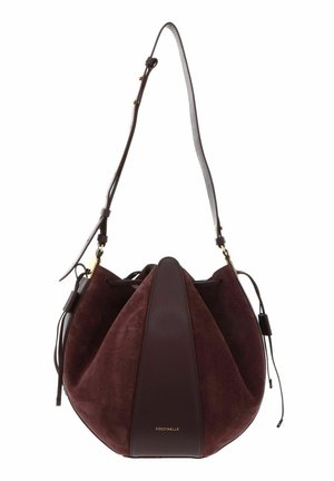 Sac seau en daim et cuir marron foncé avec bandoulière réglable et fermeture à cordon, marqué "Coccinelle" sur le panneau avant.