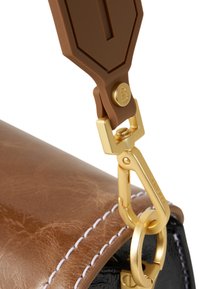 Detail van een bruine leren tas met een gouden clasp en bevestiging. Opvallende witte stiksels contrasteren met een zwarte achtergrondtextuur.