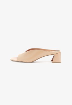 Zueco beige de punta abierta con tacón bajo de bloque y parte superior de cuero suave, mostrado en perfil lateral sobre fondo blanco.