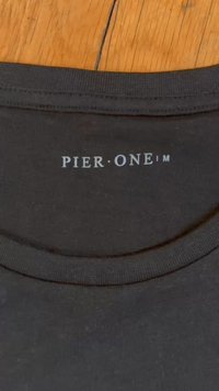 Black cotton T-shirt collar with a ribbed texture, featuring white printed text "PIER·ONE™" in a modern font.