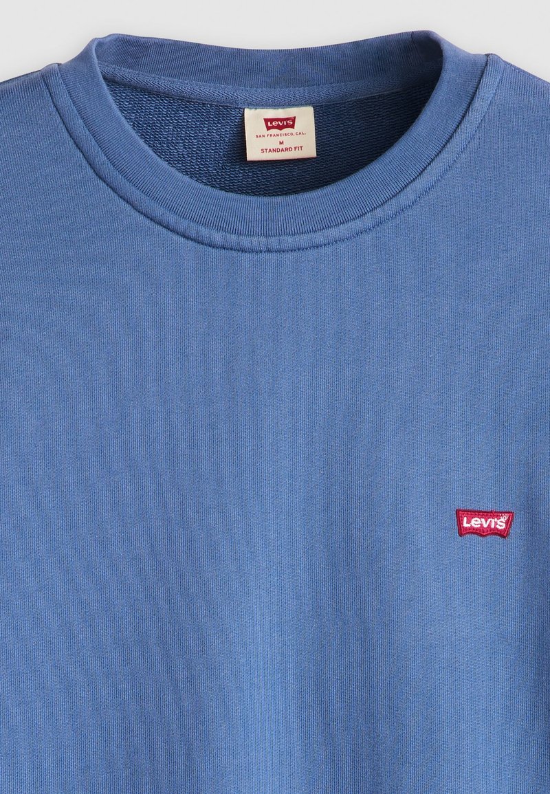 Sweatshirt bleu en coton à col rond avec col côtelé, doté d'un petit logo rouge Levi's sur la poitrine gauche. Coupe standard, texture douce.