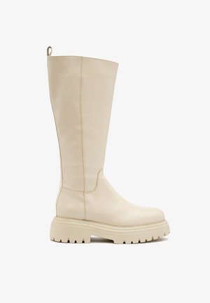 Kozaki do kolan w kremowej skórze, z grubą, teksturowaną podeszwą oraz minimalistycznym designem, o gładkiej powierzchni i subtelnych detalach w szwie.