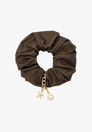 Kobieta w brązowym bikini z pierścieniowymi detalami pozuje z rękami za głową, a jej długie włosy związane są dopasowaną gumką na jednolitym tle.