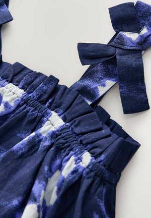 Robe marine à bretelles froncées et taille rassemblée, présentant un motif floral texturé dans des teintes blanches et violettes.