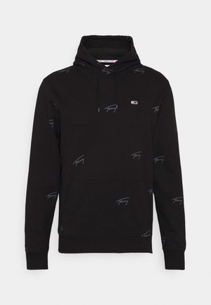 Zwarte hoodie met voorzak, trekkoord aan de capuchon, klein Tommy Jeans-logo op de borst en een subtiel herhaald "Tommy" tekstpatroon over de hele stof.