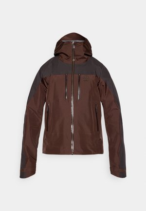 Chaqueta impermeable marrón con acentos negros, que presenta un cierre de cremallera en la parte delantera, dos bolsillos en el pecho y capucha ajustable. Acabado texturizado y puños reforzados.