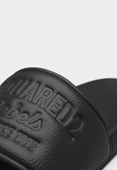 Μαύρη υφασμάτινη σαγιονάρα με ανάγλυφη επιγραφή "DSQUARED2" και "Since 1995" στο λουράκι.