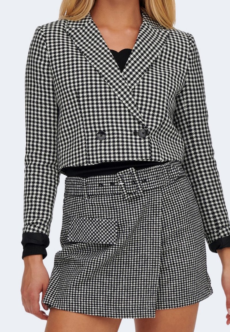 Černobílý houndstooth krátký blejzr s dvojitými knoflíky, spárovaný s odpovídající zavinovací sukní s boční kapsou.